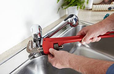 plumber holding a wrench on a faucet